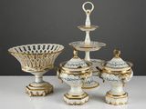 quatre pièces de porcelaine ornées de motifs dorés et blancs, posées sur une table