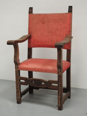 une vieille chaise en bois dont l'assise est recouverte de tissu rouge