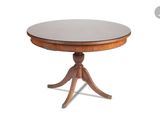 une table ronde avec un piètement en bois et un plateau en verre