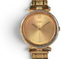 a gold watch on a gold bracelet on a white surface