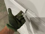 a hand that is holding a glove that is on top of a washing machine