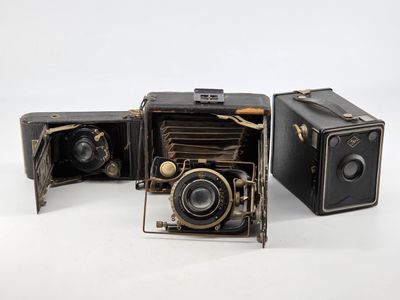 two old cameras sitting next to each other on a white surface