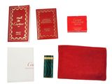 un assortiment d'articles rouges et dorés, comprenant un portefeuille rouge, un porte-cartes rouge et un mouchoir rouge