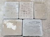 quatre sous-verres en pierre posés les uns à côté des autres sur un sol carrelé