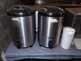 two stainless steel coffee urns sitting on top of a blue towel