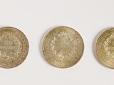 trois pièces d'or superposées sur une surface blanche