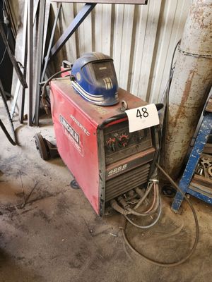 une soudeuse dans le garage, avec un casque posé dessus