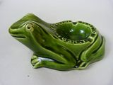 un cendrier en forme de grenouille verte posé sur une table blanche