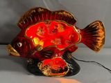 a red fish that is sitting on a black base
