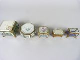 six pieces of porcelain and gold - plated furniture are lined up on a white surface