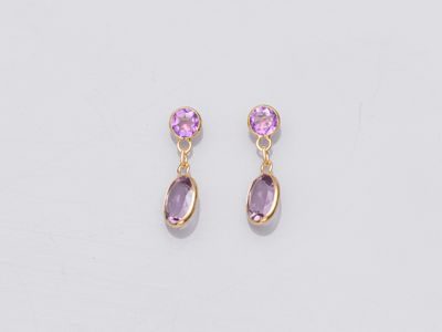 une paire de boucles d'oreilles ornées de pierres violettes sur fond blanc