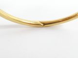 a close up of a gold bang bracelet with a curved design