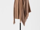 un manteau marron posé sur un mannequin, devant un fond blanc