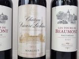 three bottles of red wine are lined up on a table
