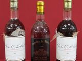 three bottles of wine are lined up on a red surface