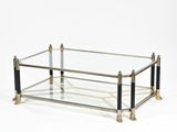 une table basse en verre et laiton avec deux pieds noirs