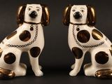 paire de figurines de chiens blanches et marron, avec des chaînes autour du cou