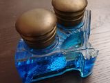 une petite bouteille en verre bleu ornée de deux boutons dorés