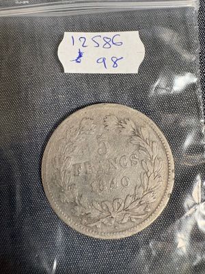 une pièce d'argent dans un sachet en plastique sur lequel est collée une étiquette