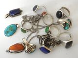 several different rings and pendants are arranged on a white surface