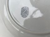 a white plate that has a silver emblem on it