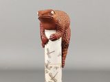 une figurine représentant une grenouille assise au sommet d'un pilier