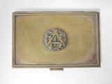 brass business card case with a crest and laurels on the front