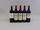 quatre bouteilles de vin sont alignées sur une surface blanche