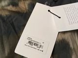 the back of a jacket with a tag on it sitting on a bed