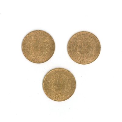 trois pièces d'or sont représentées sur une surface blanche
