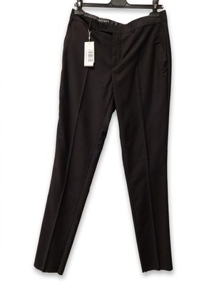 Le pantalon noir est suspendu à un cintre accroché à un mur blanc.