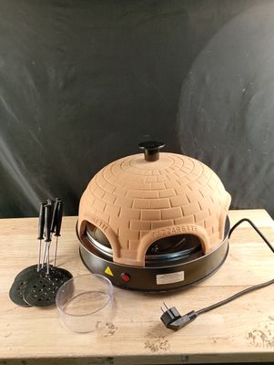 a pizza oven sitting on top of a wooden table