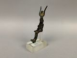 statue en bronze représentant un homme tenant un oiseau, posée sur un socle transparent