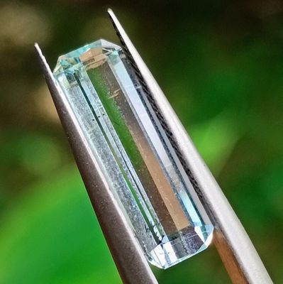 quelqu'un tient une pince dans laquelle est sertie un cristal vert
