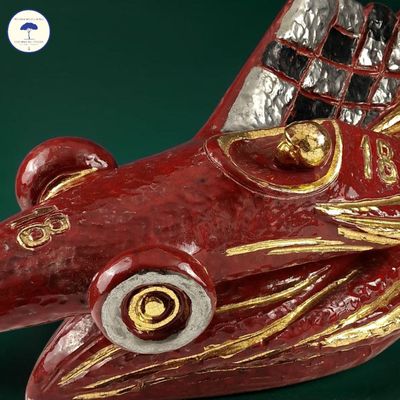 a red and gold sculpture of a fish on a green surface
