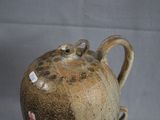 a brown vase with a flower on it on a table