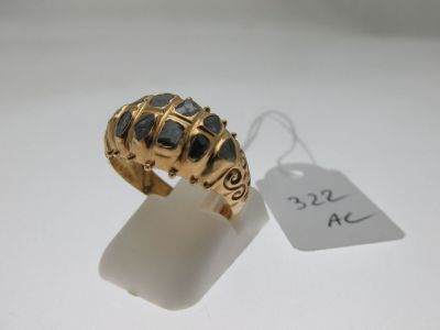 une image représentant une bague en or sertie de pierres noires sur un fond blanc