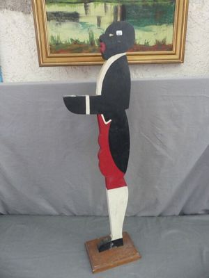 une statue représentant un homme debout sur un socle en bois