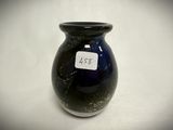 a black vase with a tag on it sitting on a table