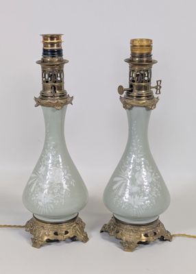 une paire de lampes anciennes en verre avec des pieds en laiton, sur fond blanc