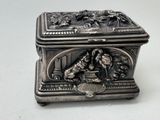 une boîte en argent sur laquelle est représenté un homme et un chien
