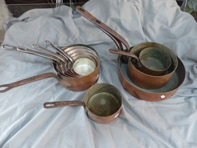 plusieurs casseroles et poêles posées sur une table recouverte d'une nappe bleue