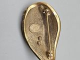 an image of a gold brooch with a pin in the shape of a leaf