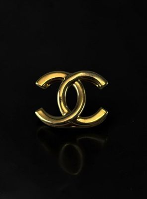 a chanel gold ring on a black surface