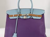 un sac à main violet et bleu posé sur une table blanche