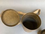 two old metal pots and a cup on a table