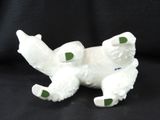 a white cat figurine with green eyes on a black background