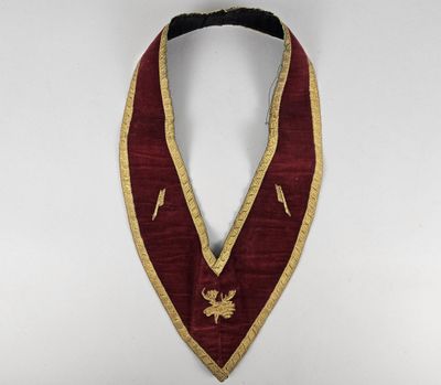 a close up of a red and gold collar on a white background