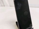 a black cell phone sitting on a stand on a white surface