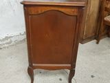 a wooden cabinet with a mirror on top of it next to a chair